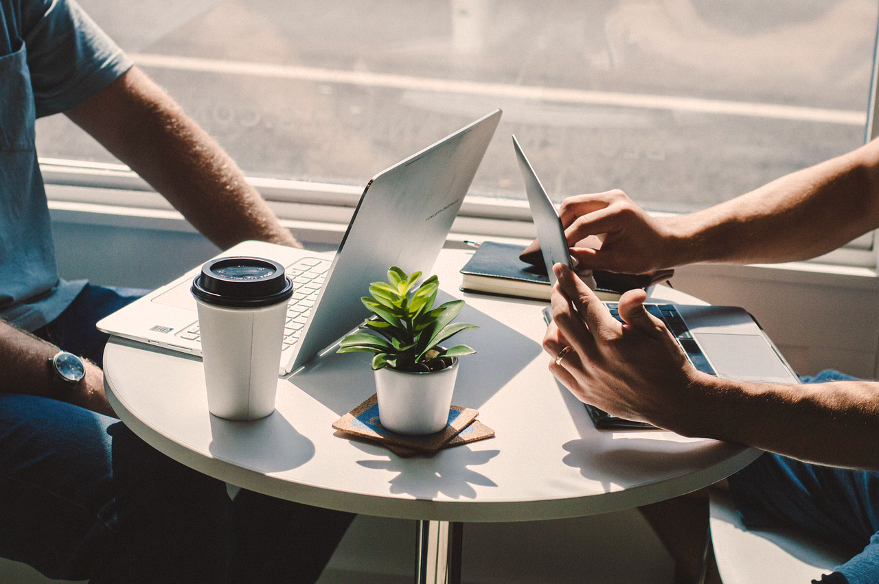 Deux entrepreneurs travaillant sur ordinateur autour d’un café.