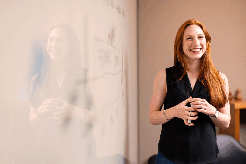 Femme souriante présentant devant un tableau blanc dans un bureau