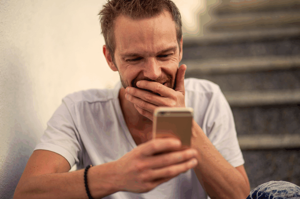 Homme souriant en consultant son smartphone.